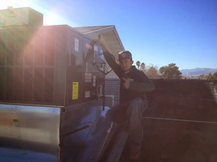 HVAC technician performing Boiler Repair on a rooftop unit in Neosho
